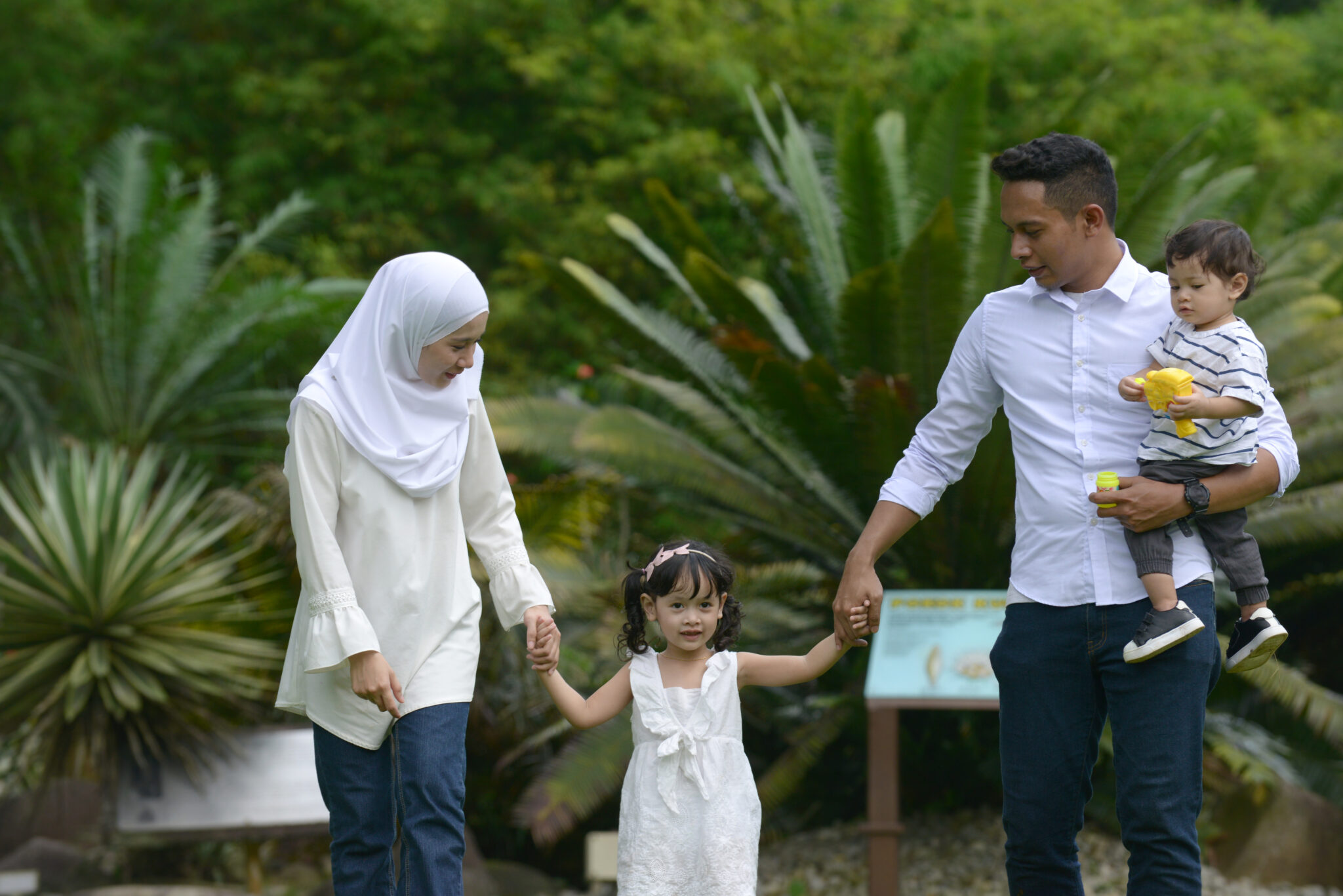malay family enjoying quality time with father, son , mother and daughter in park